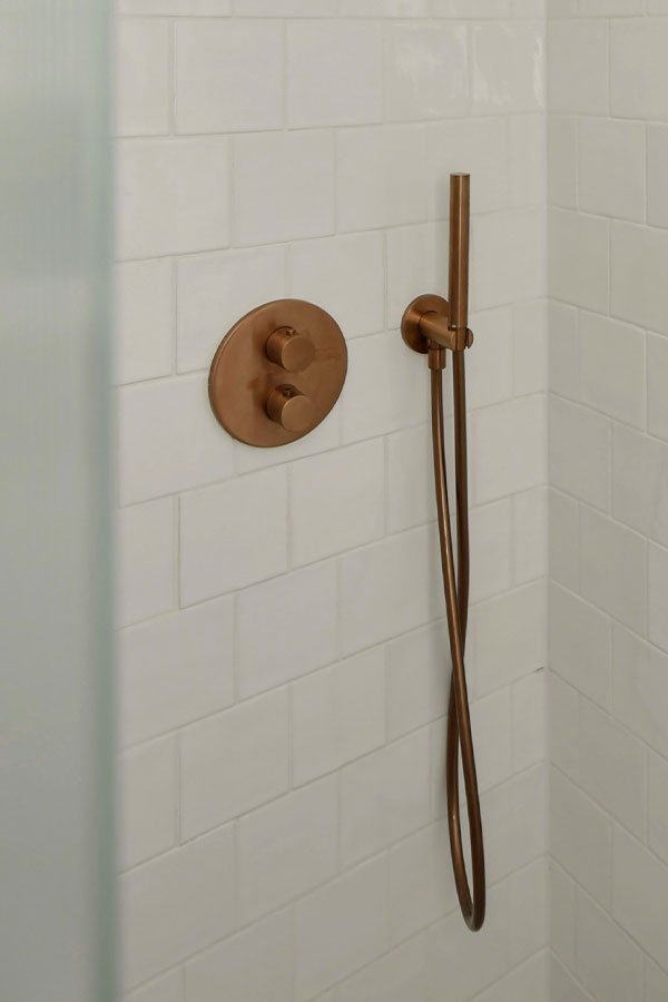 Witte tegels koperen douchekraan