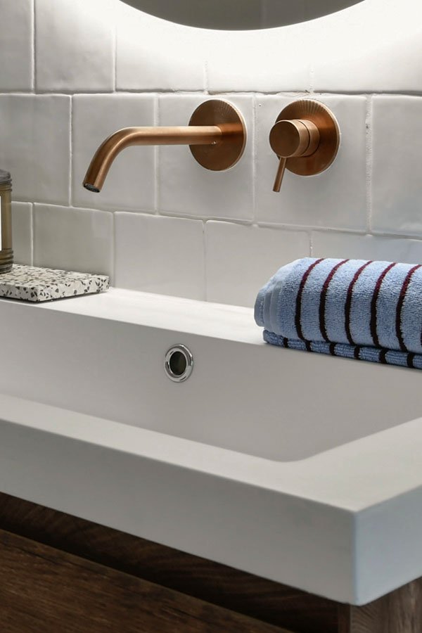 Witte tegels koperen wastafelkraan