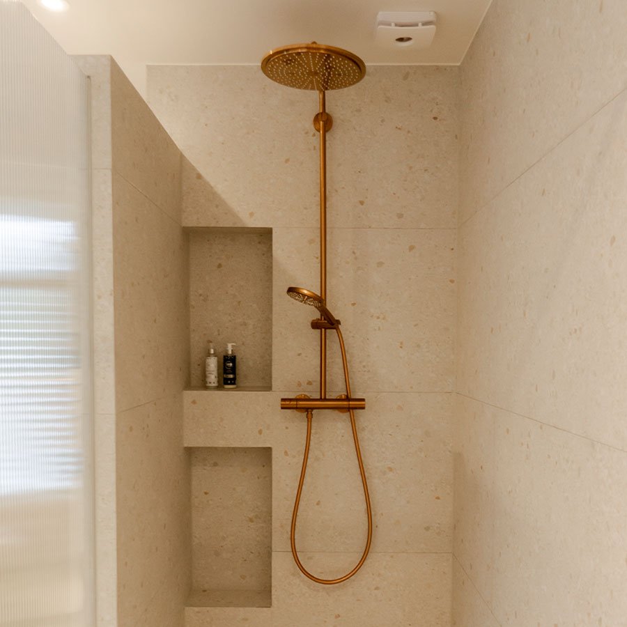 Beige douche met koperen kraan bij Caroline