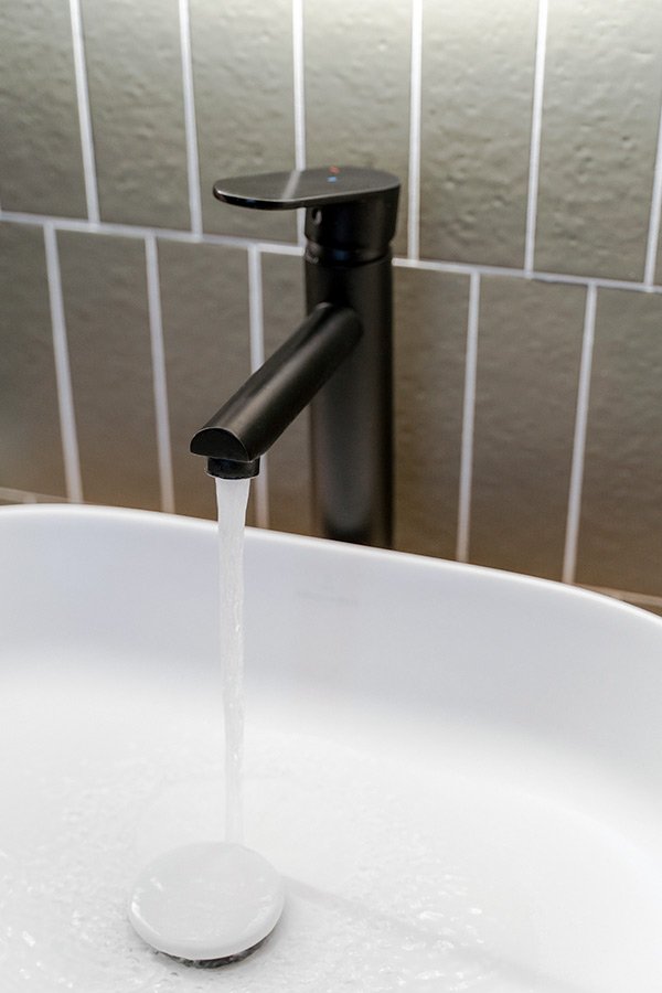 Zwarte wastafelkraan groene tegels