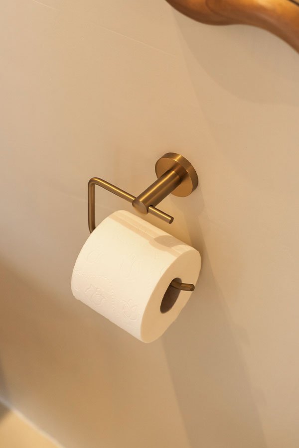 Porte-rouleau doré dans un espace toilettes beige