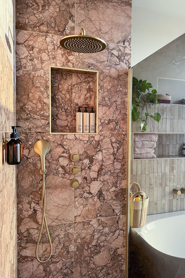 Doucheruimte met een donkerrode natuursteen tegel en gouden kranen