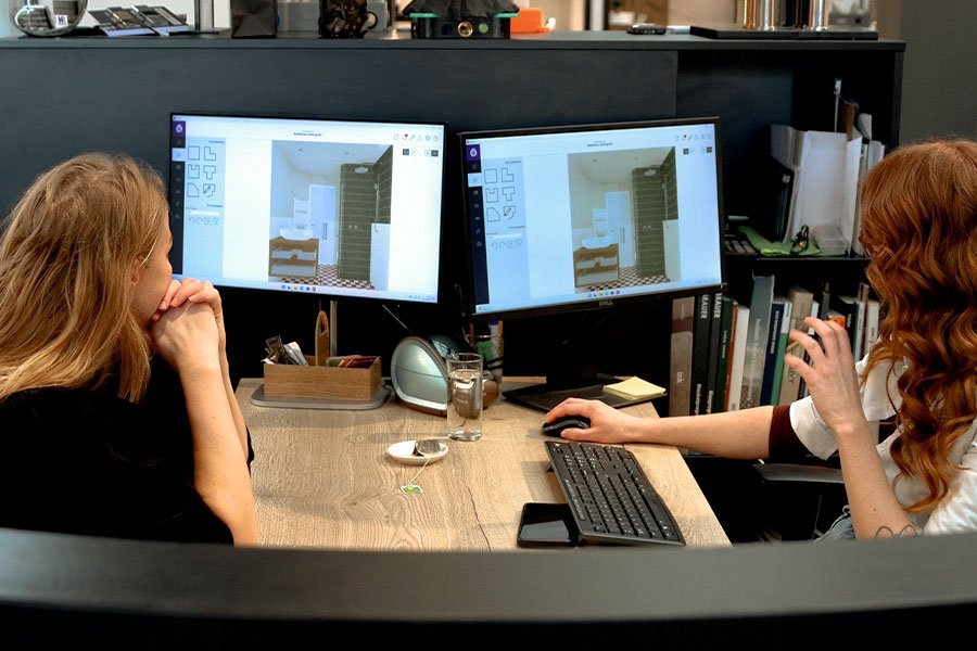 twee mensen zitten achter de computer om badkamer te ontwerpen