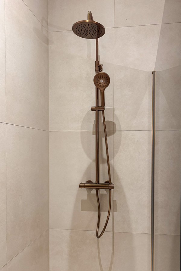 carreaux muraux beiges avec système de douche en cuivre